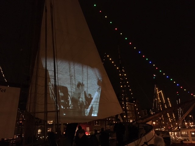 Een filmvoorstelling op een van de zeilen van een afgemeerd schip
