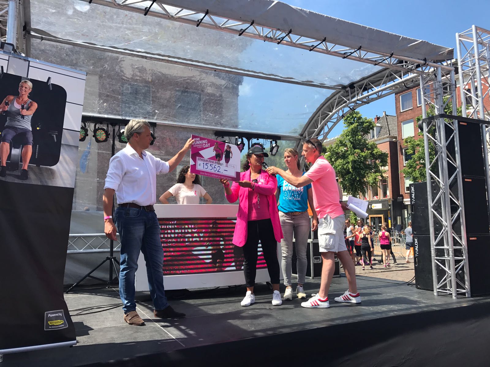 De cheque met de opbrengst wordt overhandigd aan Grace Bregman van Pink Ribbon.