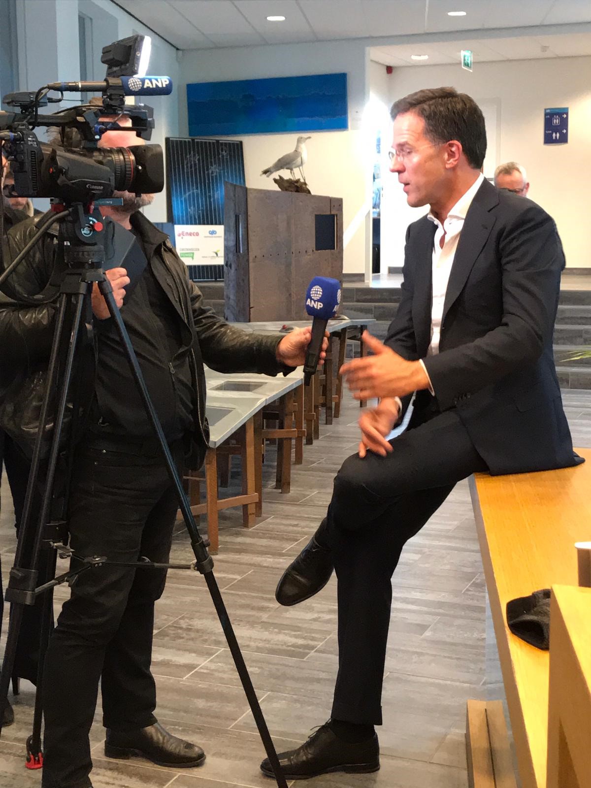De vermoeidheid slaat een klein beetje toe: de premier gaat er even bij zitten na alle interviews.