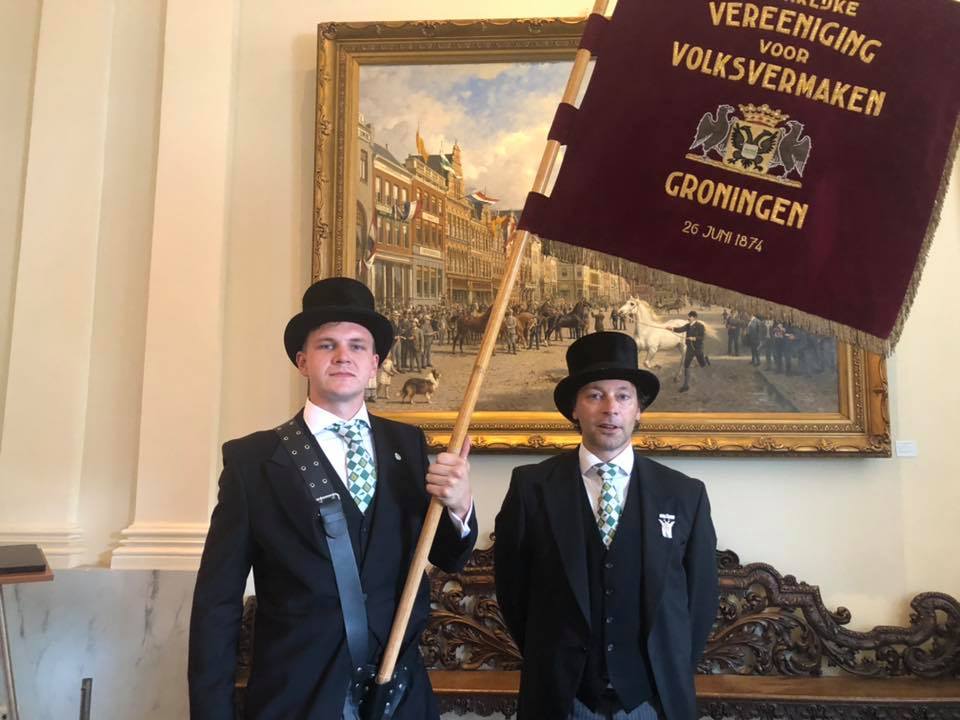 Vaandeldragers van Volksvermaken bij het beroemde schilderij van 28 augustus van Otto Eerelman