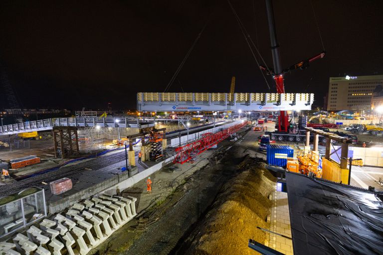 Het hijsen van de brugdekken over de hulpbrug over het spoor